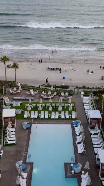 Aerial view of the beach, the surf and palm trees at Coronado Beach, with people walking.