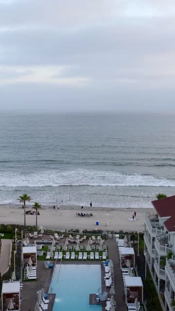Aerial view of the beach, the surf and palm trees at Coronado Beach, with people walking.