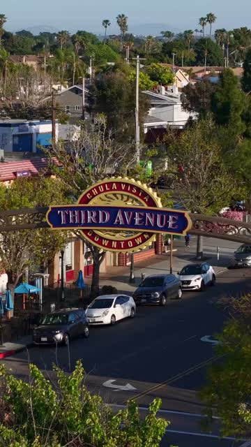Low aerial view of the downtown streets, palm trees and the buildings in Chula Vista, with people walking.