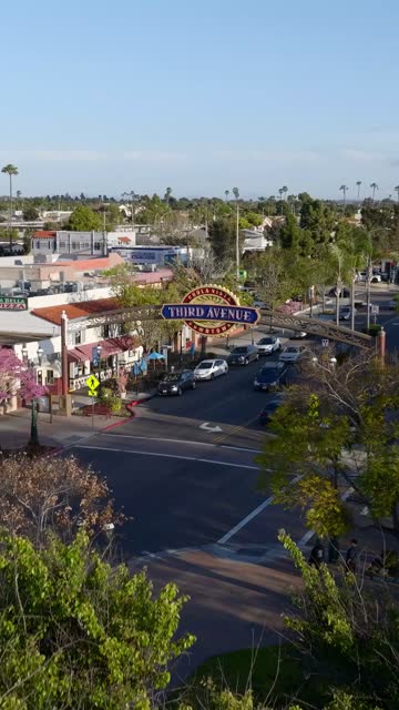 Low aerial view of the downtown streets, palm trees and the buildings in Chula Vista, with people walking.