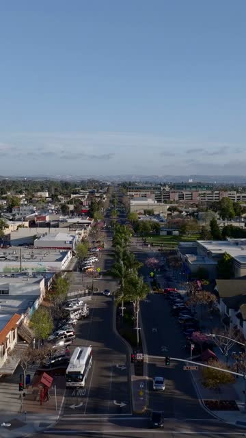 Low aerial view of the downtown streets, palm trees and the buildings in Chula Vista, with people walking.