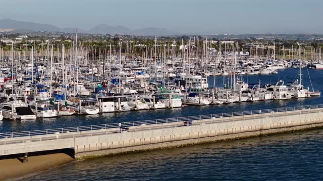 Low aerial view of the harbor, boats and the bay in Chula Vista, with people walking.