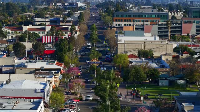 Low aerial view of the downtown streets, palm trees and the buildings in Chula Vista, with people walking.
