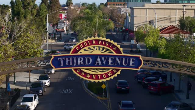 Low aerial view of the downtown streets, palm trees and the buildings in Chula Vista, with people walking.