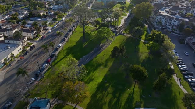Low aerial view of a park, palm trees and homes in Chula Vista, with people walking.