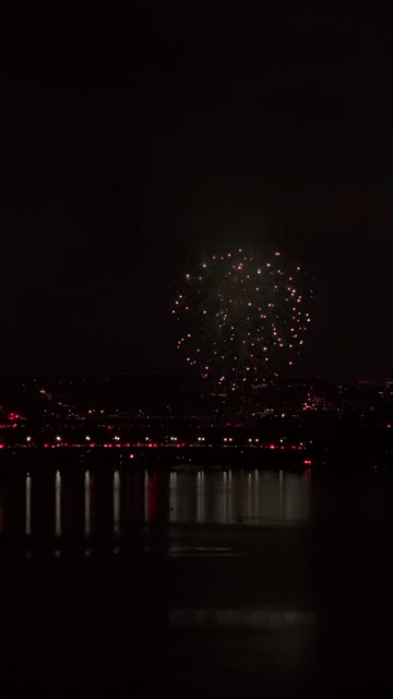 Mission Bay at night with 4th of July fireworks reflecting across the water and packed shoreline in San Diego