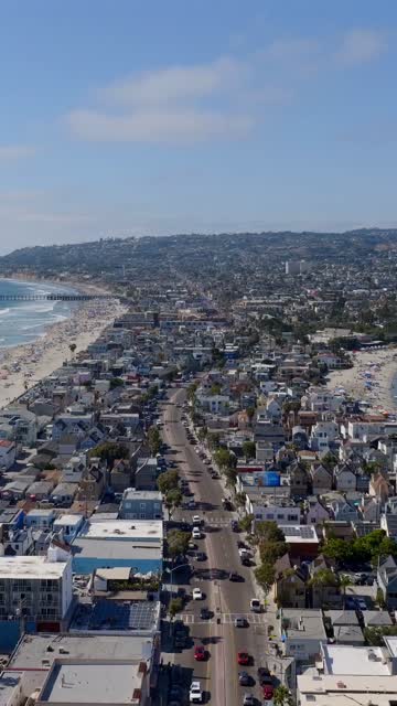 Aerial view of the beach, the pier and the ocean in Mission Bay, with a crowd gathered.