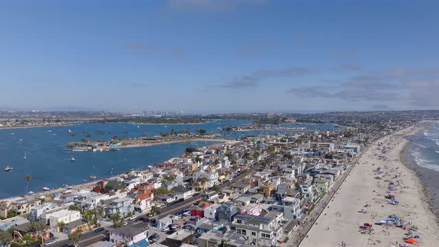Aerial view of the beach, boats and the ocean in Mission Bay, with a crowd gathered.