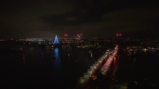 Aerial view of the harbor, the bridge and boats in Mission Bay, with a crowd gathered.
