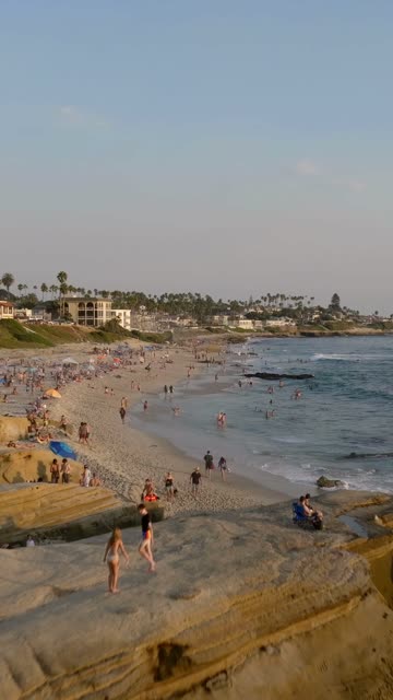 Beautiful afternoon at Windansea Beach in La Jolla with crowds enjoying the sun and beach activities at one of the most iconic beaches in San Diego | Vertical Drone Video – 2