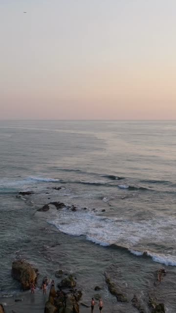 Aerial view of the cliffs, the surf and the ocean at Beach Barber Tract, with people walking.