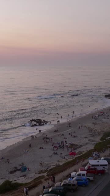Aerial view of the beach, the surf and the ocean at Beach Barber Tract, with a crowd gathered.