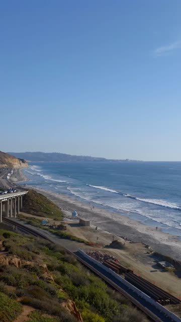Elevated view of the cliffs, the surf and the ocean at Torrey Pines, with people walking.