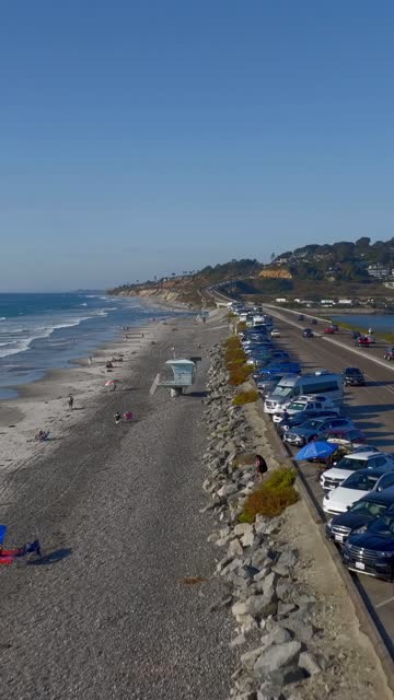 Aerial view of the beach, the surf and the ocean at Torrey Pines, with people walking.