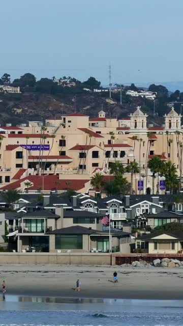 Elevated view of a residential street, palm trees and the ocean in Del Mar, with people walking.