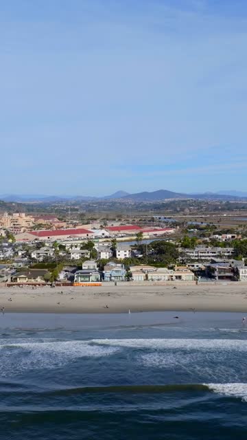 Aerial view of the beach, the surf and the ocean in Del Mar, with people walking.