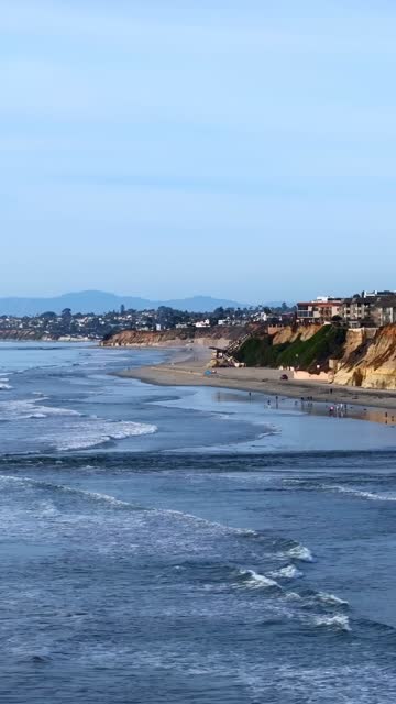 Aerial view of the beach, the surf and the ocean in Del Mar, with people walking.