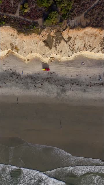 Aerial view of the beach, the surf and the ocean in Del Mar, with people walking.