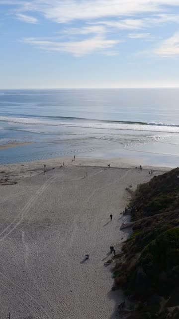 Aerial view of the beach, the surf and the ocean in Del Mar, with people walking.