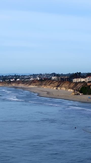 Aerial view of the beach, the surf and the ocean in Del Mar, with people walking.
