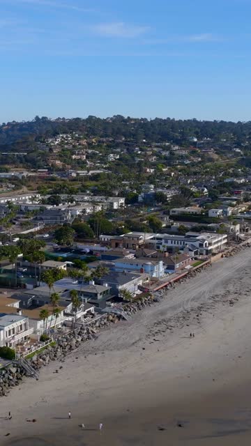 Aerial view of the beach, palm trees and the ocean in Del Mar, with people walking.