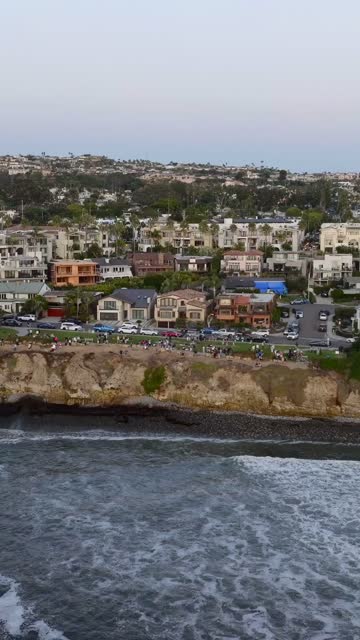 Aerial view of the cliffs, the ocean and homes at Bird Rock, with people walking.