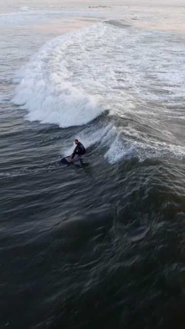 Low aerial view of the beach, the surf and the ocean at Bird Rock, with surfers out.