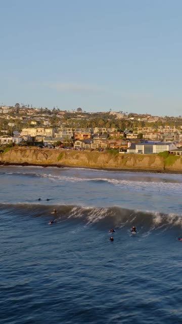 Low aerial view of the beach, the surf and the ocean at Bird Rock, with surfers out.