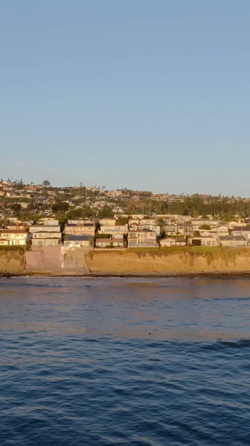 Low aerial view of the cliffs, the ocean and homes at Bird Rock.