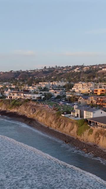 Aerial view of the cliffs, the surf and the ocean at Bird Rock, with people walking.
