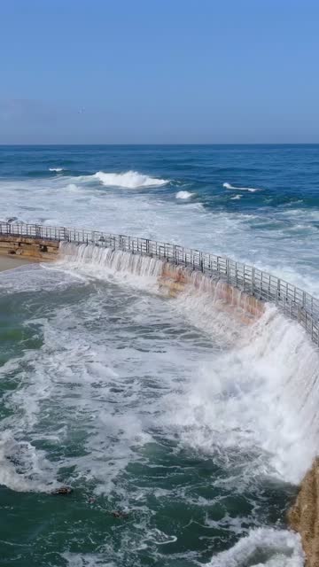 Low aerial view of the beach, the surf and the ocean at Village of La Jolla.
