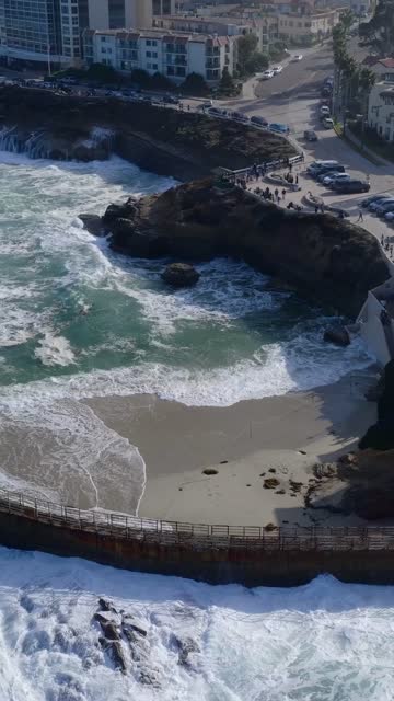 Aerial view of the cliffs, the surf and the ocean at Village of La Jolla, with people walking.