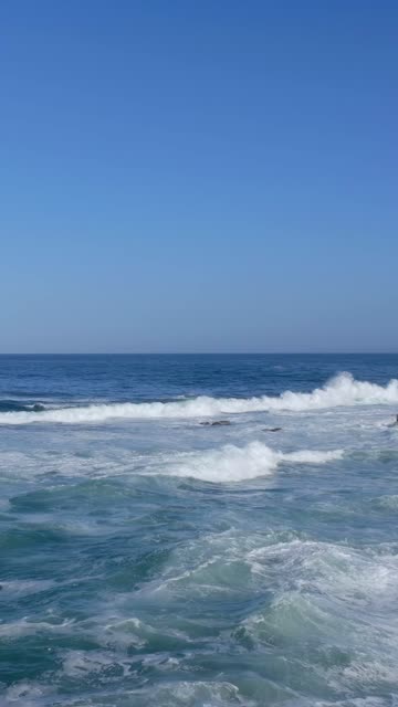 Low aerial view of the beach, the surf and the ocean at Village of La Jolla.