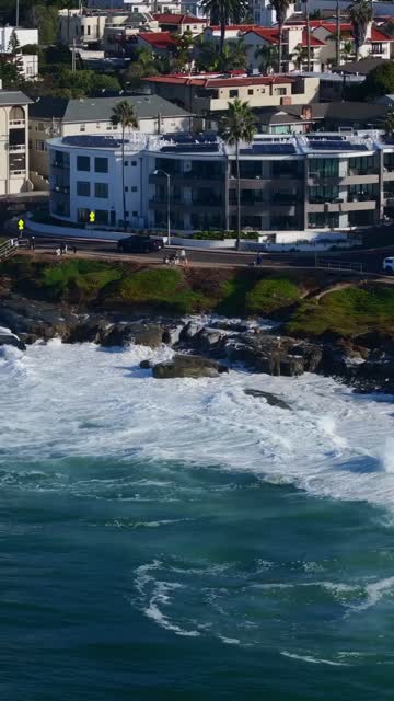 Aerial view of the cliffs, the surf and palm trees at Beach Barber Tract, with people walking.