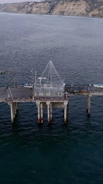 Low aerial view of the beach, the pier and boats at Black’s Beach.