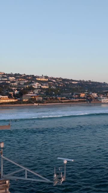 Low aerial view of the beach, the surf and the ocean at Black’s Beach, with surfers out.