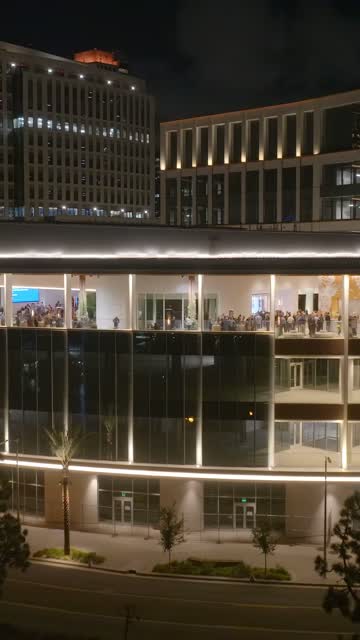Low aerial view of the downtown streets, palm trees and the buildings at Embarcadero, with a crowd gathered.