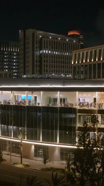 Low aerial view of the downtown streets, the skyline and palm trees at Embarcadero, with a crowd gathered.