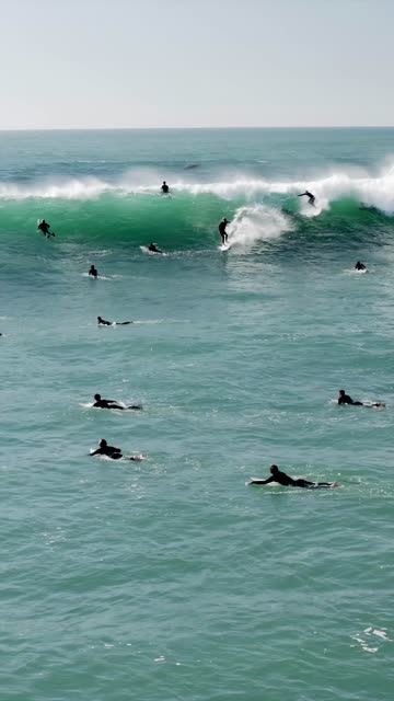 Low aerial view of the beach, the surf and the ocean at Swamis, with surfers out.