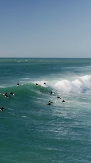 Low aerial view of the beach, the surf and the ocean at Swamis, with surfers out.