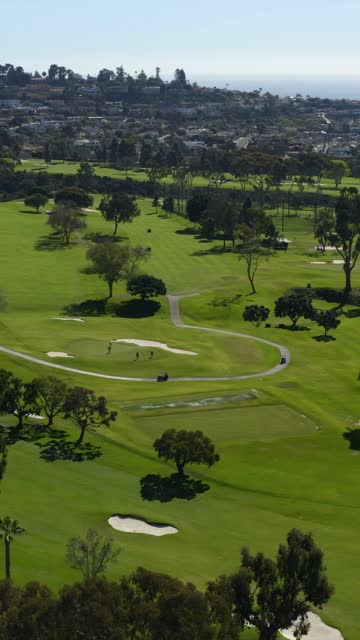 Aerial view of a park, the ocean and homes at La Jolla Country Club, with people walking.