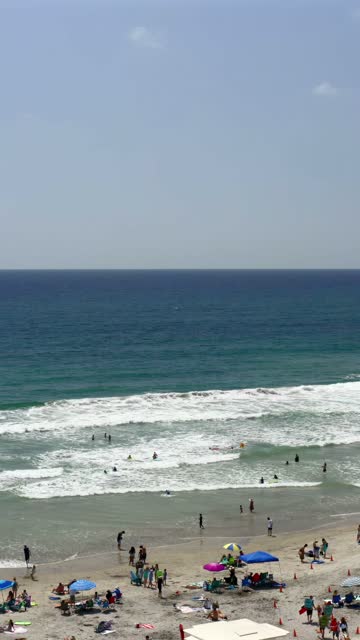 Aerial view of the beach, the surf and the ocean at Moonlight Beach, with swimmers in the water.