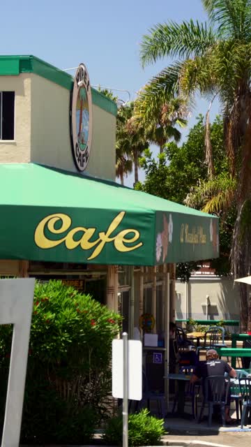 The downtown streets, palm trees and the buildings in Cardiff, with people eating outside.