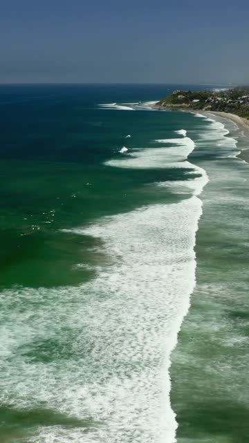 Aerial view of the beach, the surf and the ocean in Cardiff, with surfers out.