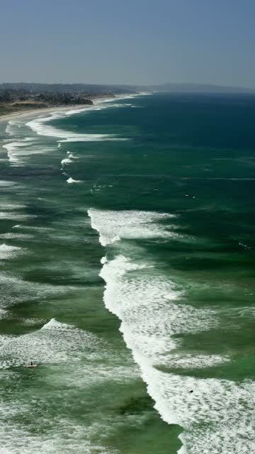 Aerial view of the beach, the surf and the ocean in Cardiff, with surfers out.