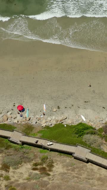 Aerial view of the beach, the surf and the ocean in Cardiff, with people walking.
