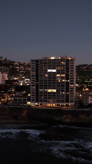 Low aerial view of the cliffs, the ocean and homes at La Jolla Cove.