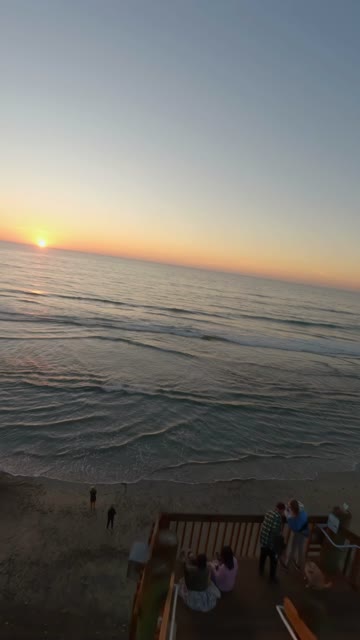 Aerial view of the beach, the surf and the ocean in Encinitas, with a crowd gathered.
