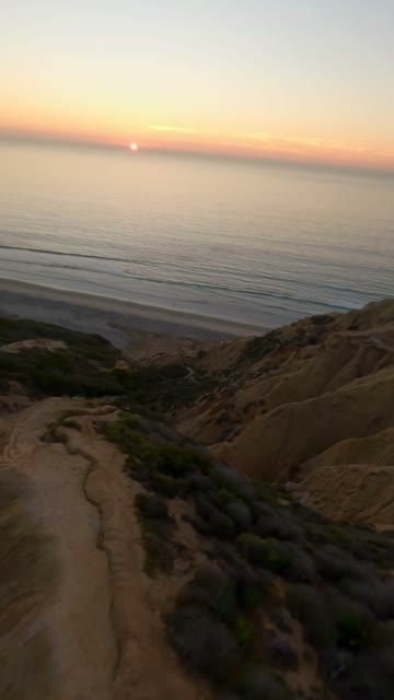 Low aerial view of the cliffs, the ocean and the beach at Black’s Beach.