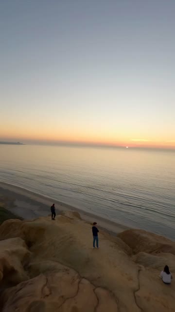 Elevated view of the cliffs, the ocean and the beach at Black’s Beach, with people walking.